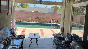 En täckt uteplats med en pool, utemöbler och en takfläkt.