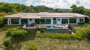 Une maison moderne dotée d’une piscine, de panneaux solaires et d’un jardin luxuriant.