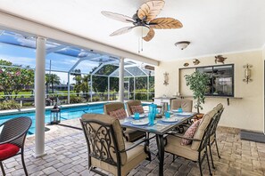 Une terrasse extérieure avec une piscine, une table à manger et des chaises.