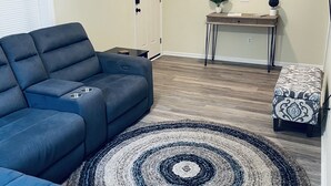 A living room with a blue sofa, a round rug, a desk, and a painting on the wall. - Unit C, Spirit of Folly, Pet Friendly,  2 short blocks - 100 yards to the beach (Folly Beach)