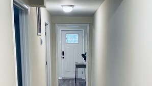 A hallway with a starfish rug, a basket of laundry, and a door at the end. - Unit C, Spirit of Folly, Pet Friendly,  2 short blocks - 100 yards to the beach (Folly Beach)