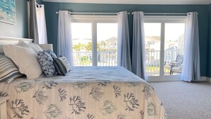 Une chambre à coucher avec un lit, des oreillers et une vue sur un balcon.
