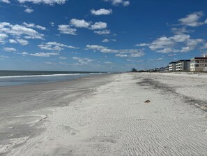 Ein Strand mit klarem Himmel und dem Ozean. Entlang der Küste befinden sich Gebäude.