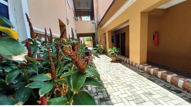 A corridor with a tiled floor, potted plants, and a fire extinguisher on the wall. - Studio C in gated Lekki estate - 5min from a beach (Lekki Phase 1)