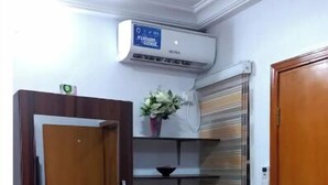 A room with a wooden desk, a chair, a mirror, a shelf with a vase, and a radiator. - Studio C in gated Lekki estate - 5min from a beach (Lekki Phase 1)