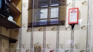 A compact kitchen with a refrigerator, a stove, and a fire blanket on the wall. - Studio C in gated Lekki estate - 5min from a beach (Lekki Phase 1)