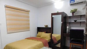 A bedroom with a bed, bedside table, mirror, chair, and a small table with chess pieces. - Studio C in gated Lekki estate - 5min from a beach (Lekki Phase 1)