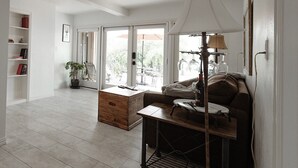 A spacious living room with a wooden coffee table, a sofa, and a floor lamp. There is a bookshelf and a potted plant in the corner. - Relaxing Lake Travis waterfront apartment with boat launch (Austin)