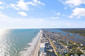 A coastal town with a beach, a pier, and residential buildings. - Garden City Beach Oceanfront Condo 1202 | Rising Tides Properties Rental (Murrells Inlet)