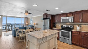 A modern kitchen with granite countertops, stainless steel appliances, and wooden cabinets. - Garden City Beach Oceanfront Condo 1202 | Rising Tides Properties Rental (Murrells Inlet)