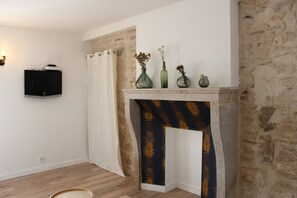 A room with a fireplace, a flat-screen TV mounted on the wall, and a wooden floor.