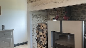 A modern living room with a stone fireplace, wooden beams, and a white cabinet. - Cottage Philmaries (Sainte-Féréole)