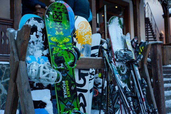 Un soporte con tablas de snowboard y esquíes, mostrando logotipos y texto de marcas, que indica una zona de alquiler o venta de equipo para deportes de invierno.