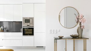 Una cucina moderna con mobili bianchi, forno in acciaio inossidabile e piano di lavoro nero.
