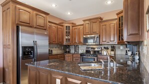 Una cocina con gabinetes de madera, electrodomésticos de acero inoxidable, encimeras de granito y horno empotrado.
