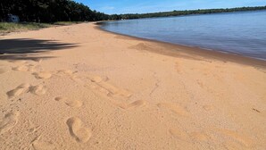 A sandy beach with footprints and a clear blue sky.