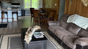 A cozy living room with a fireplace, a mounted deer head, and a dining area with wooden furniture.