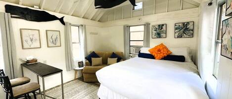 A bedroom with a bed, a desk, a chair, and a ceiling fan.