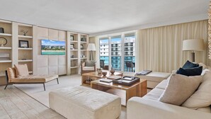 Una sala de estar moderna con un gran ventanal, un televisor de pantalla plana y vistas a un edificio.