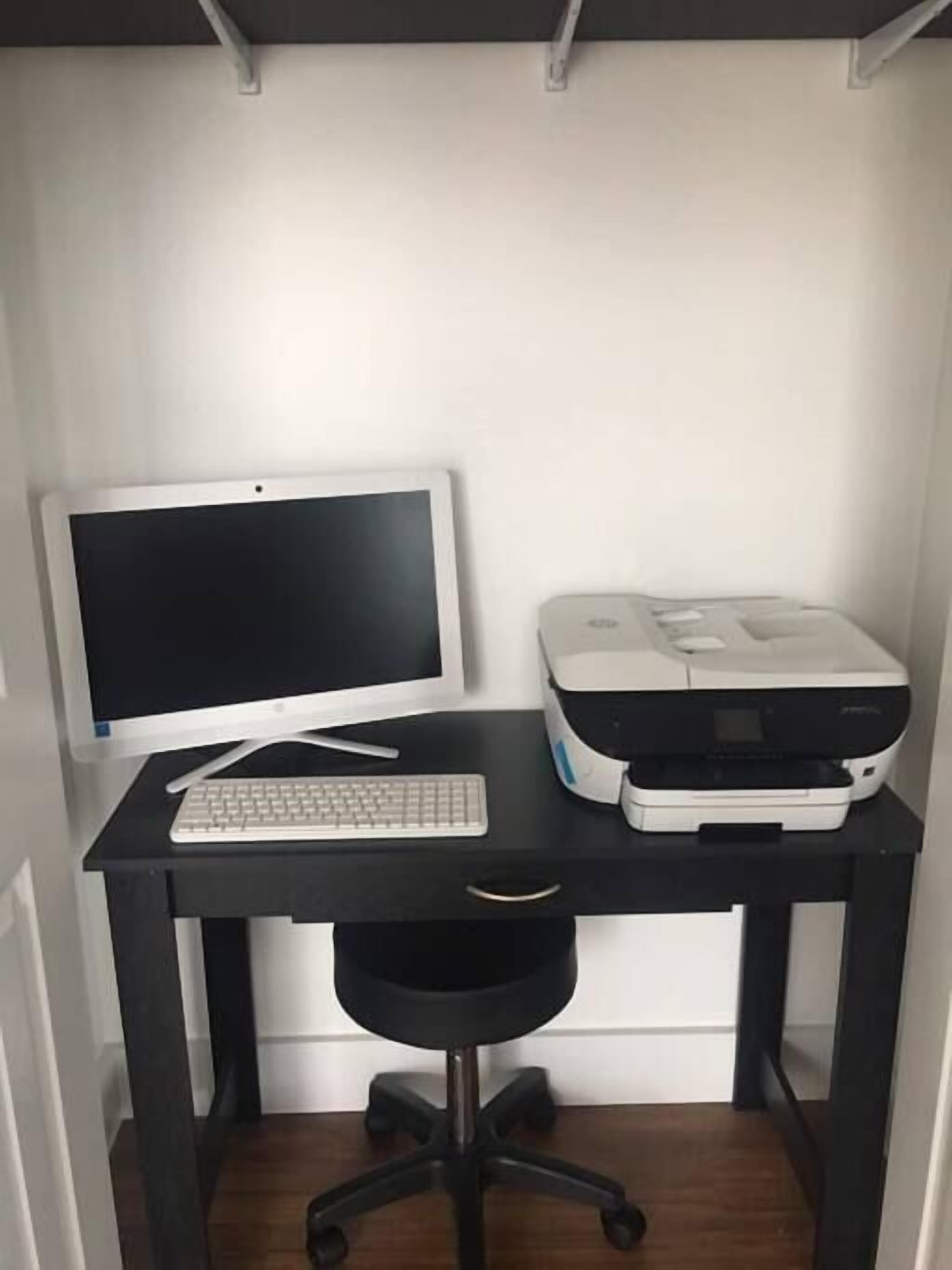 A compact office setup with a desktop computer, a printer, and a black office chair.