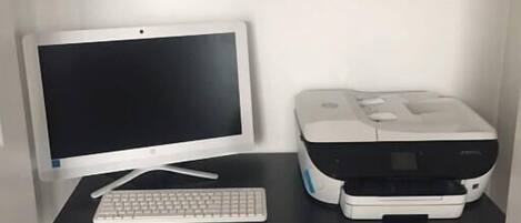 A compact office setup with a desktop computer, a printer, and a black office chair.