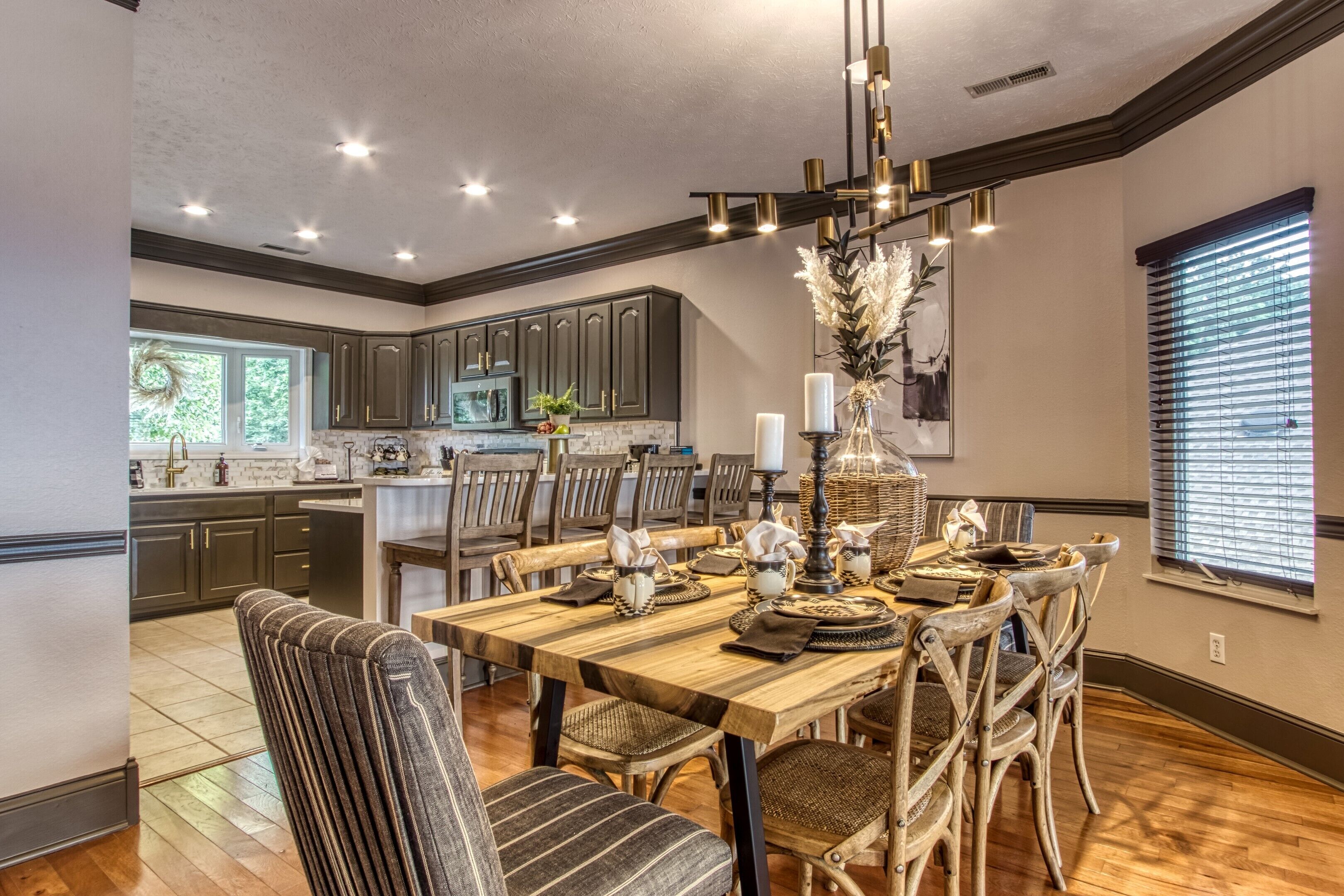A dining area with a wooden table set for six, surrounded by wicker chairs.