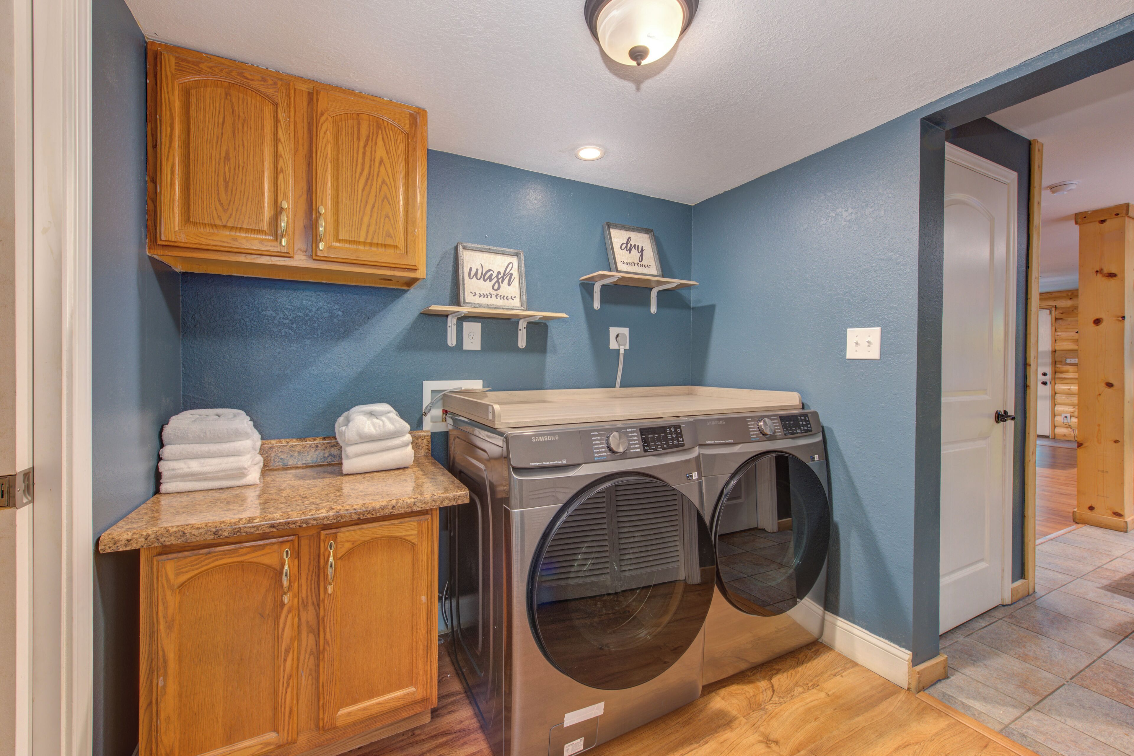A laundry room with a washing machine, wooden cabinets, and a blue wall.