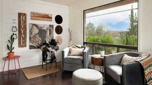 Ein modernes Wohnzimmer mit einem großen Fenster, rustikaler Wandgestaltung und einem Ledersofa.