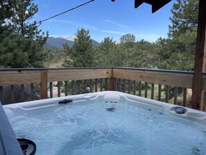 Un jacuzzi en una terraza de madera con vista a la montaña.