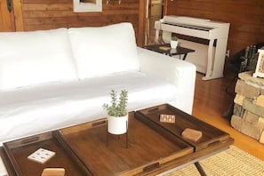A white sofa, a wooden coffee table with trays, a small potted plant, and a stone wall. - Country home, Beautiful country home with horses (Laurel Fork)