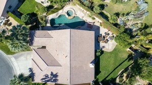 Vista aérea de una propiedad residencial con piscina, mobiliario de patio y jardines ajardinados.