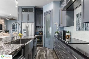 A modern kitchen with grey cabinetry, a marble countertop, and a built-in oven.