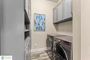 A laundry room with a washing machine, dryer, and grey cabinets.