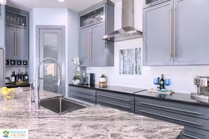 Une cuisine moderne avec des meubles gris, une hotte en acier inoxydable et un plan de travail en marbre.