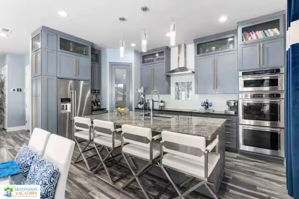 Une cuisine moderne dotée d’un îlot central, d’appareils électroménagers en acier inoxydable et de meubles de couleur bleu clair.