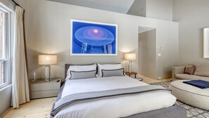 A modern hotel room with a large bed, two bedside tables, a sofa, and a large abstract painting on the wall. - Modern Vail Village Ski-in Ski-Out Townhome (Vail)
