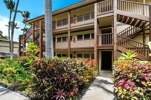 A multi-story hotel with a wooden exterior, balconies, and a staircase. - Kona Isle D2 (Kailua-Kona)