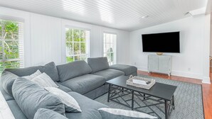 Ein modernes Wohnzimmer mit einem grauen Ecksofa, einem schwarzen Couchtisch und einem gemusterten Teppich.
