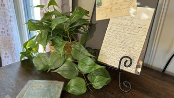 A framed letter on a stand, a potted plant, and a book on a wooden table.