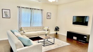 Un salon avec un canapé beige, une table basse et un téléviseur fixé au mur.