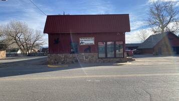 A red building with a stone base, a sign advertising a clean and comfortable room, and a parking lot in front.