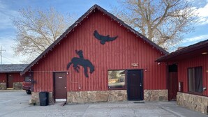 A red barn with a horse silhouette and a bird silhouette on the wall, a stone foundation, and a Titan truck parked outside. - The Sage Motel (Saratoga)