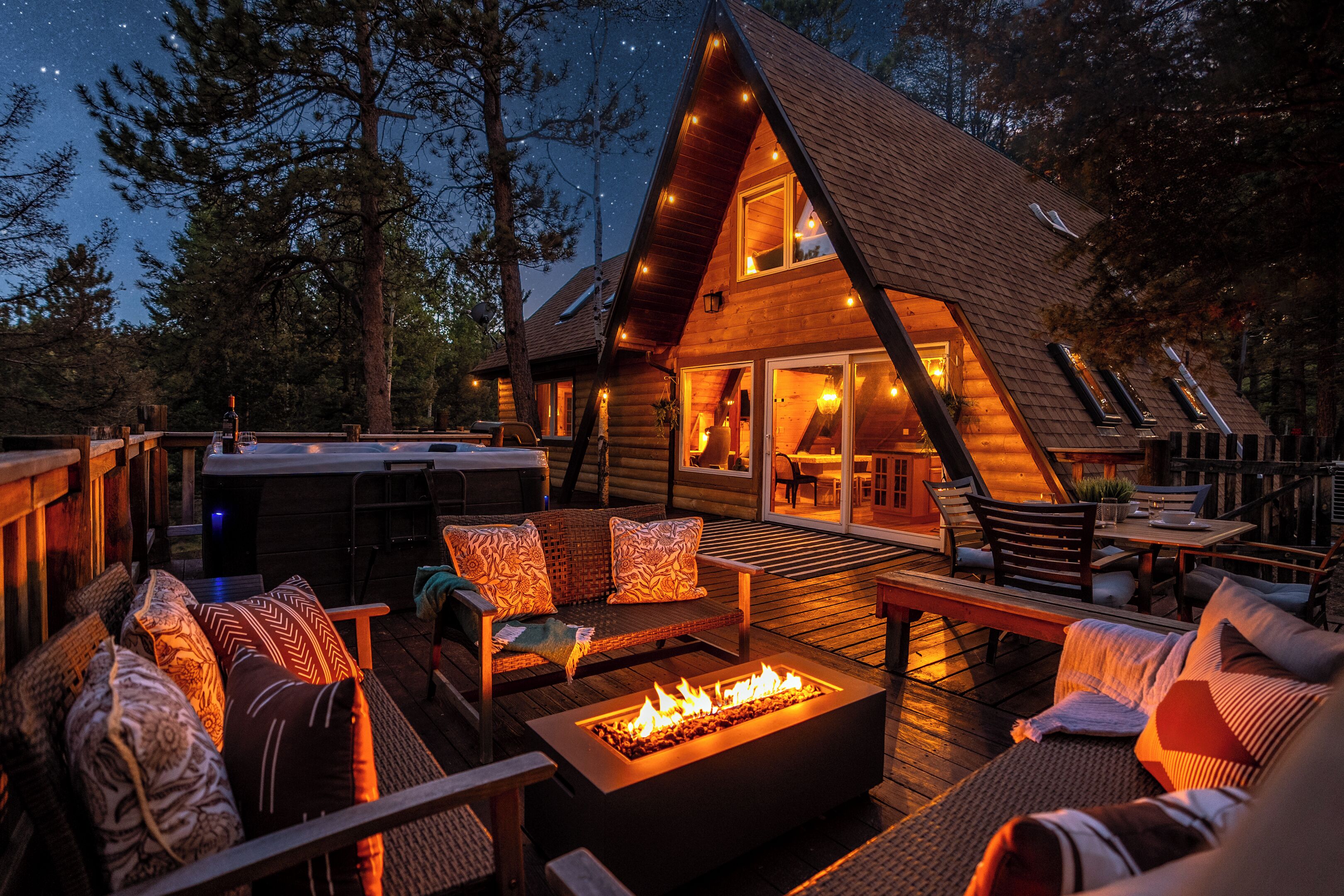 A log cabin with a deck, outdoor seating, and a fire pit.