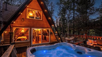 A log cabin with a hot tub and deck area.