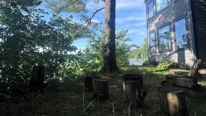 A large tree in a yard with a wooden deck and a building with multiple windows. - Lakefront Luxury Modern Home With Docks, Fire Pit & Pontoon Boat Rental (Turtle Lake)