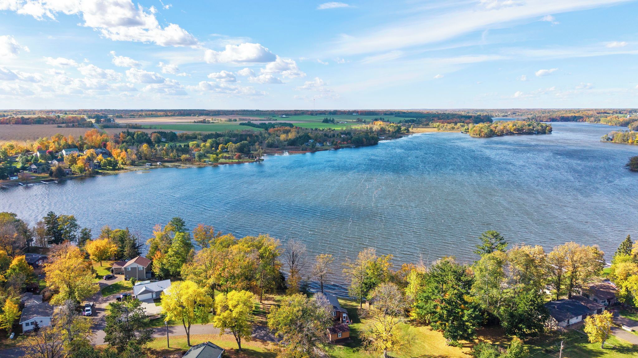 Een rivier met huizen aan de oevers, omringd door herfstkleurige bomen.