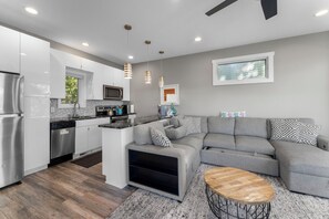 A modern kitchen with white cabinetry, a built-in microwave, and a stainless steel refrigerator. - Lakefront Luxury Modern Cabin With Docks, Fire Pit & Pontoon Boat Rental (Turtle Lake)