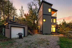 A modern two-story house with a garage, a balcony, and a well-lit entrance. - Lakefront Luxury Modern Cabin With Docks, Fire Pit & Pontoon Boat Rental (Turtle Lake)