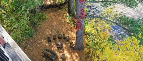 A forested area with a dirt path, a wooden bench, and a tree with red leaves.