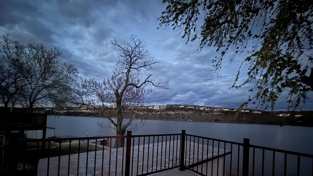 Eine Terrasse mit Feuerstelle, Blick auf einen See und ein Baum im Hintergrund.